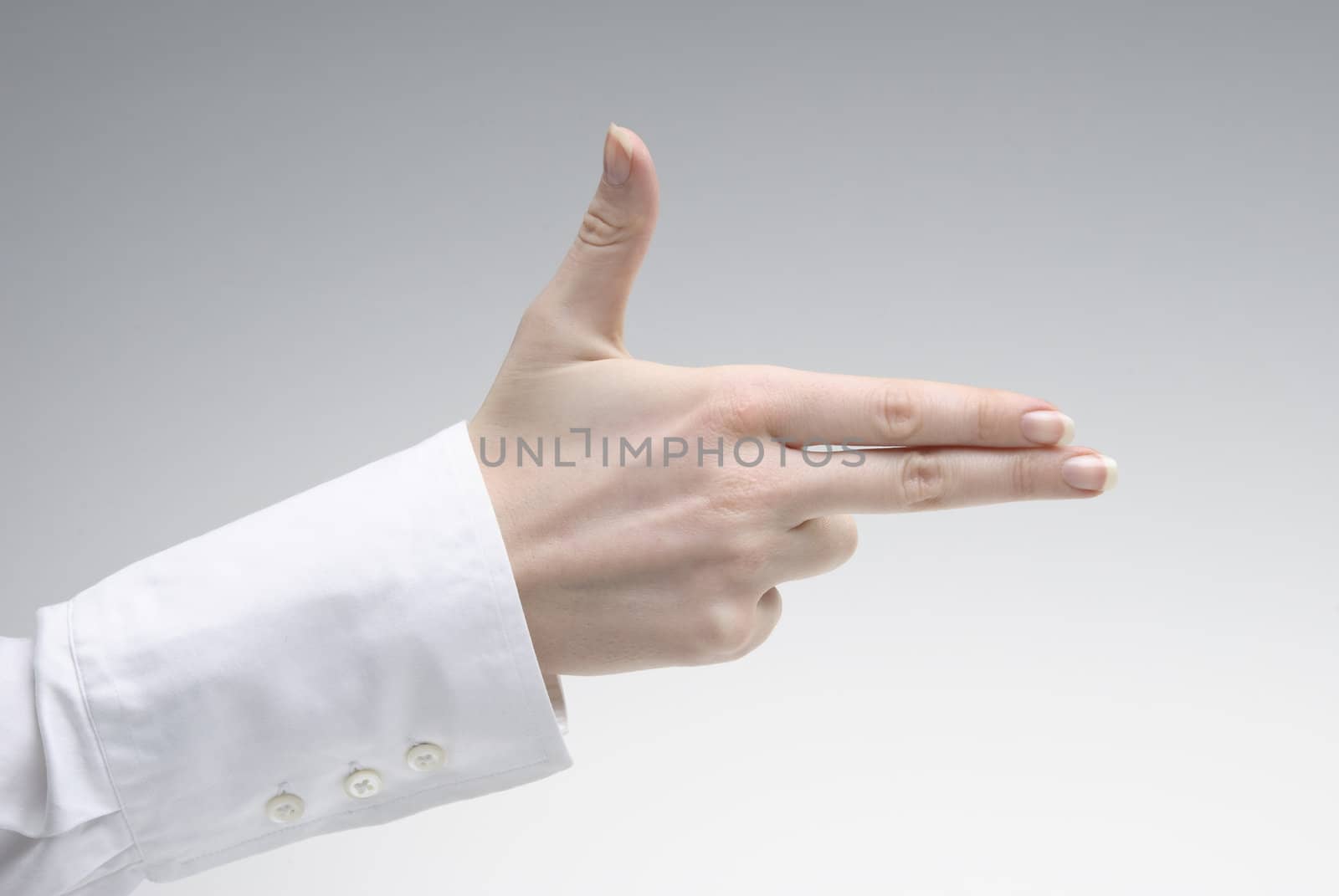 Woman's hand showing pistol symbol  over light background