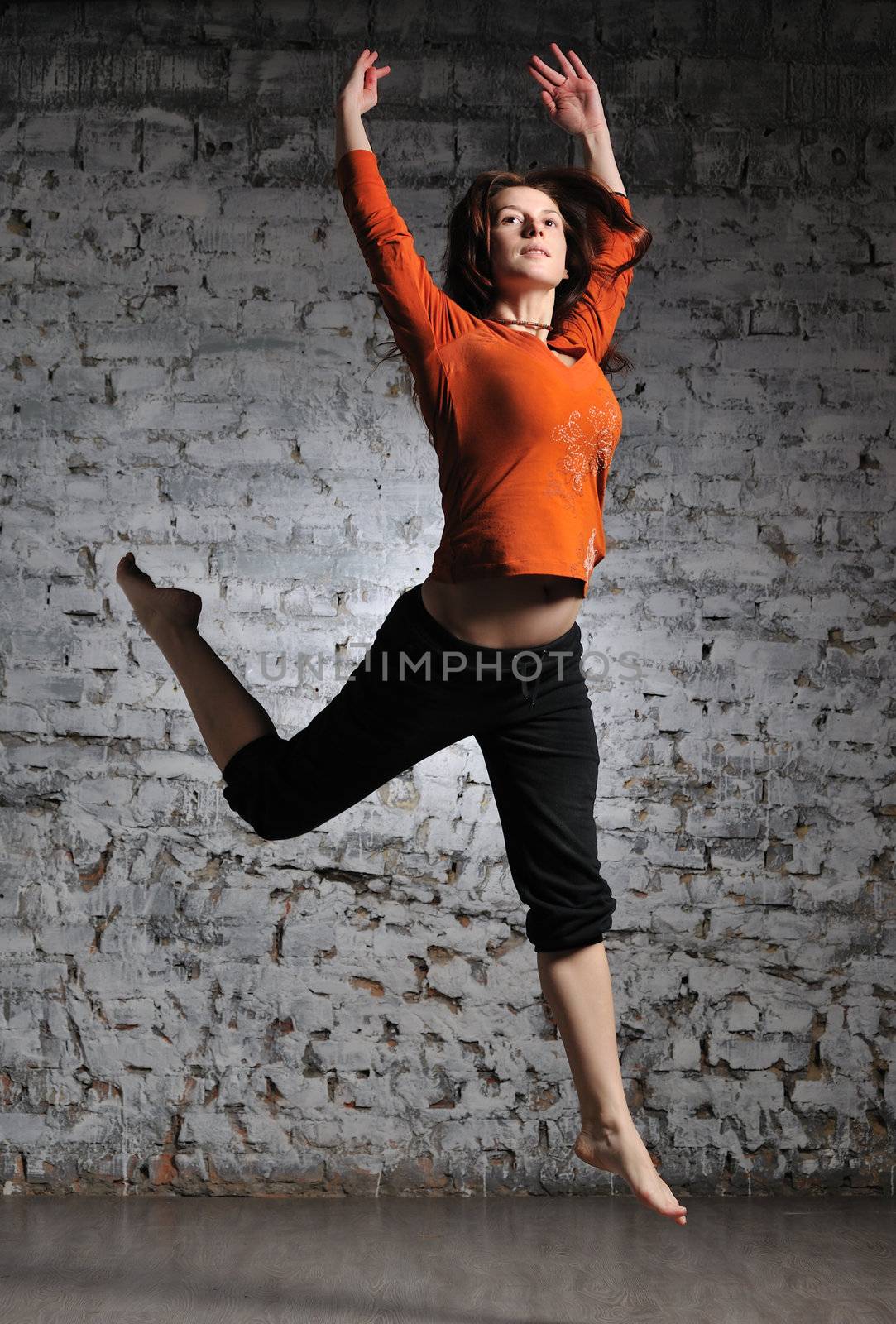 Girl in sportswear jumping on the brick wall background