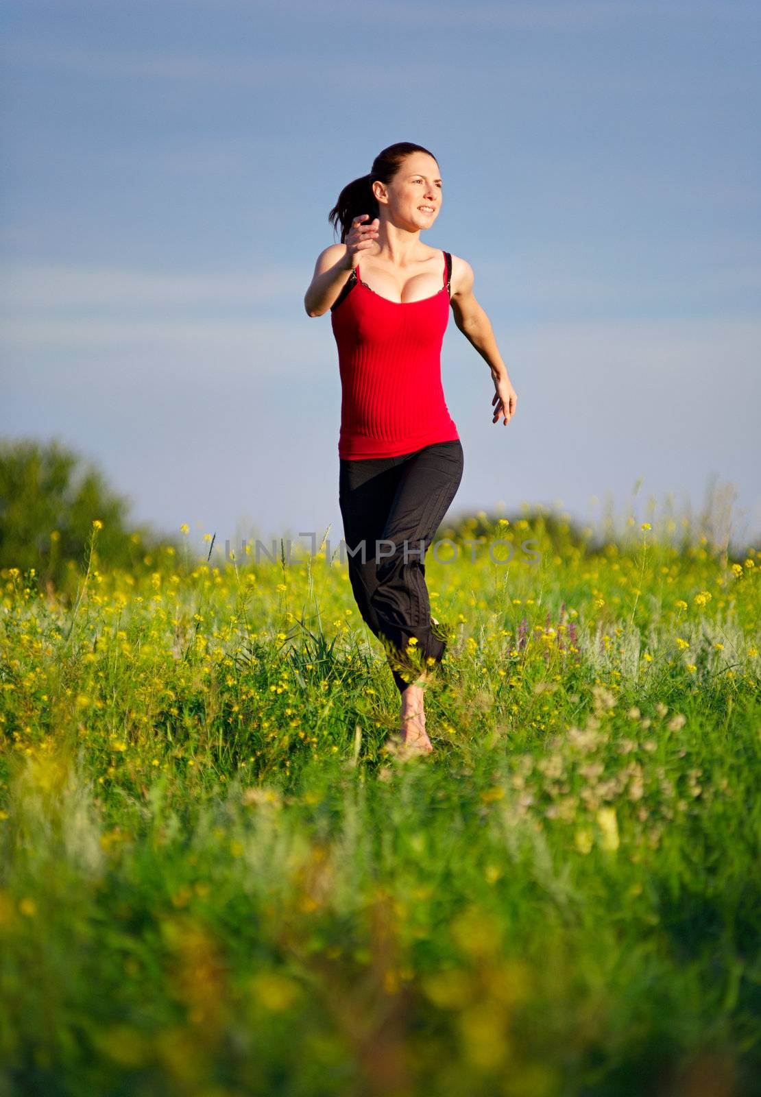 Sport woman running on a sunset field