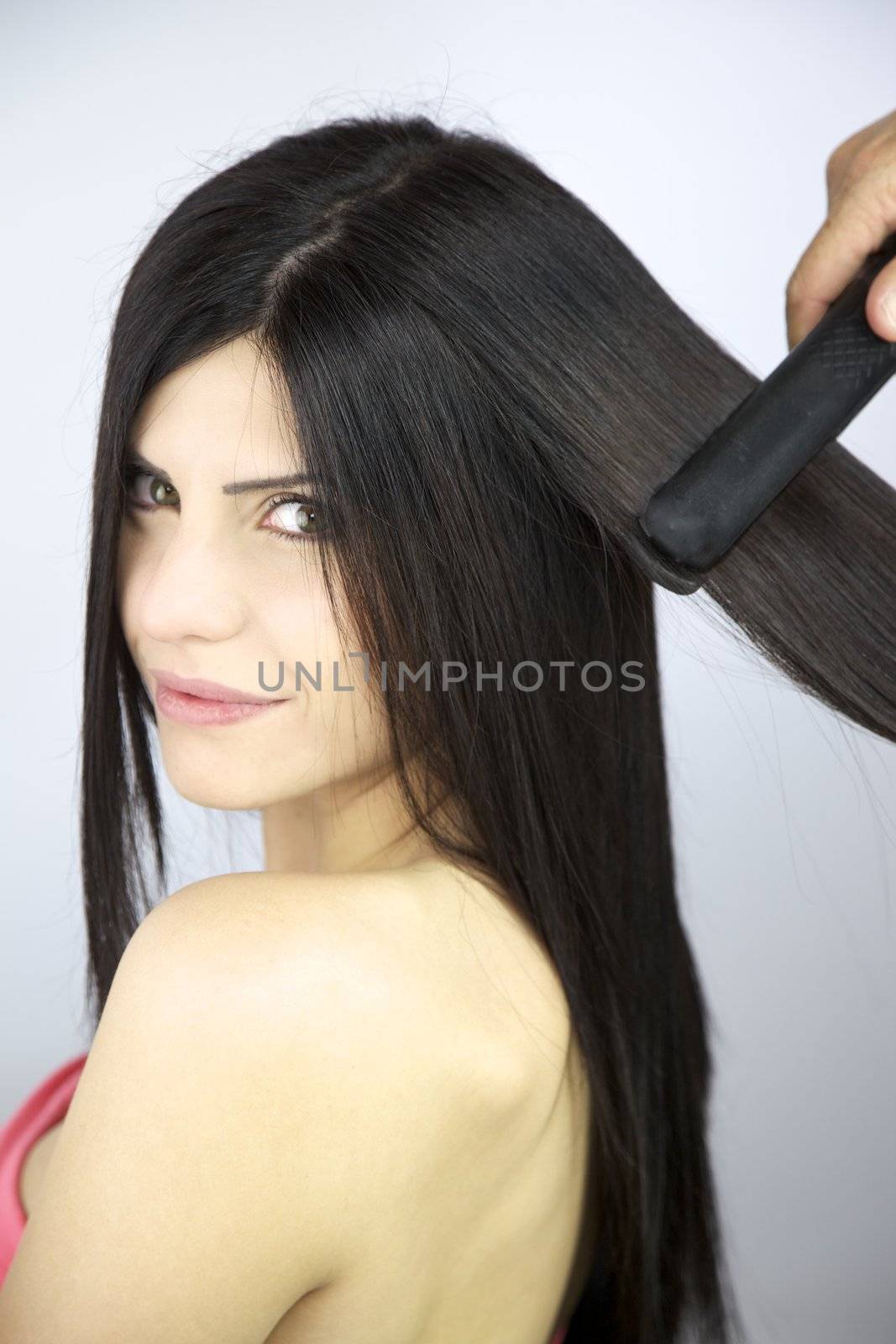 Hairdresser ironing long brunette silky hair