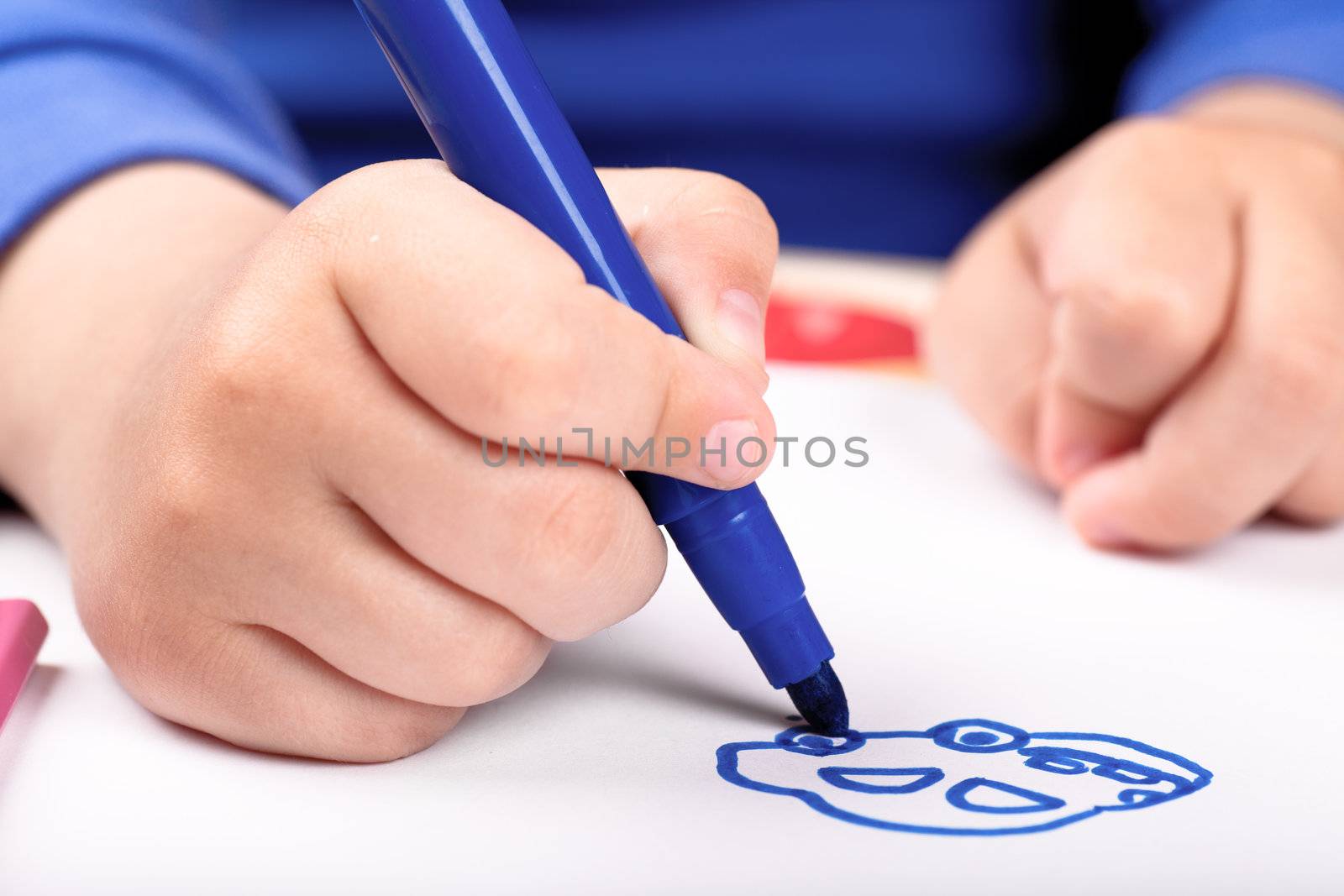 Child's hand drawing a car with blue felt pen