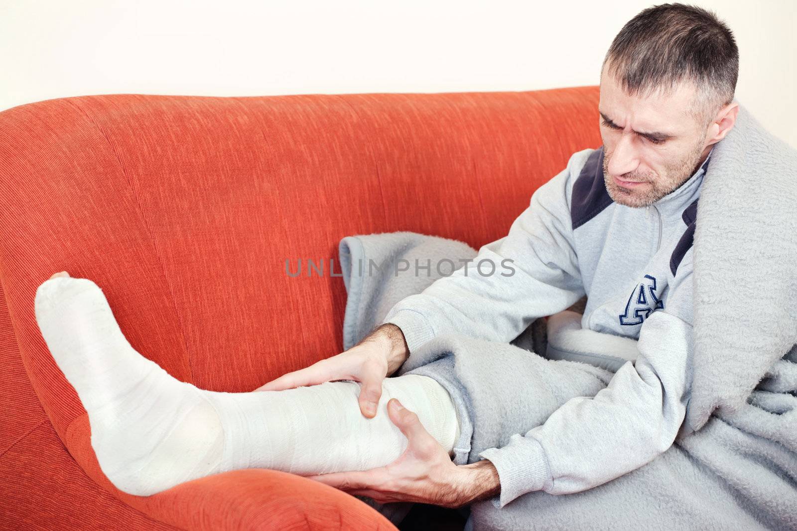 man with a broken leg on a sofa at home having pain