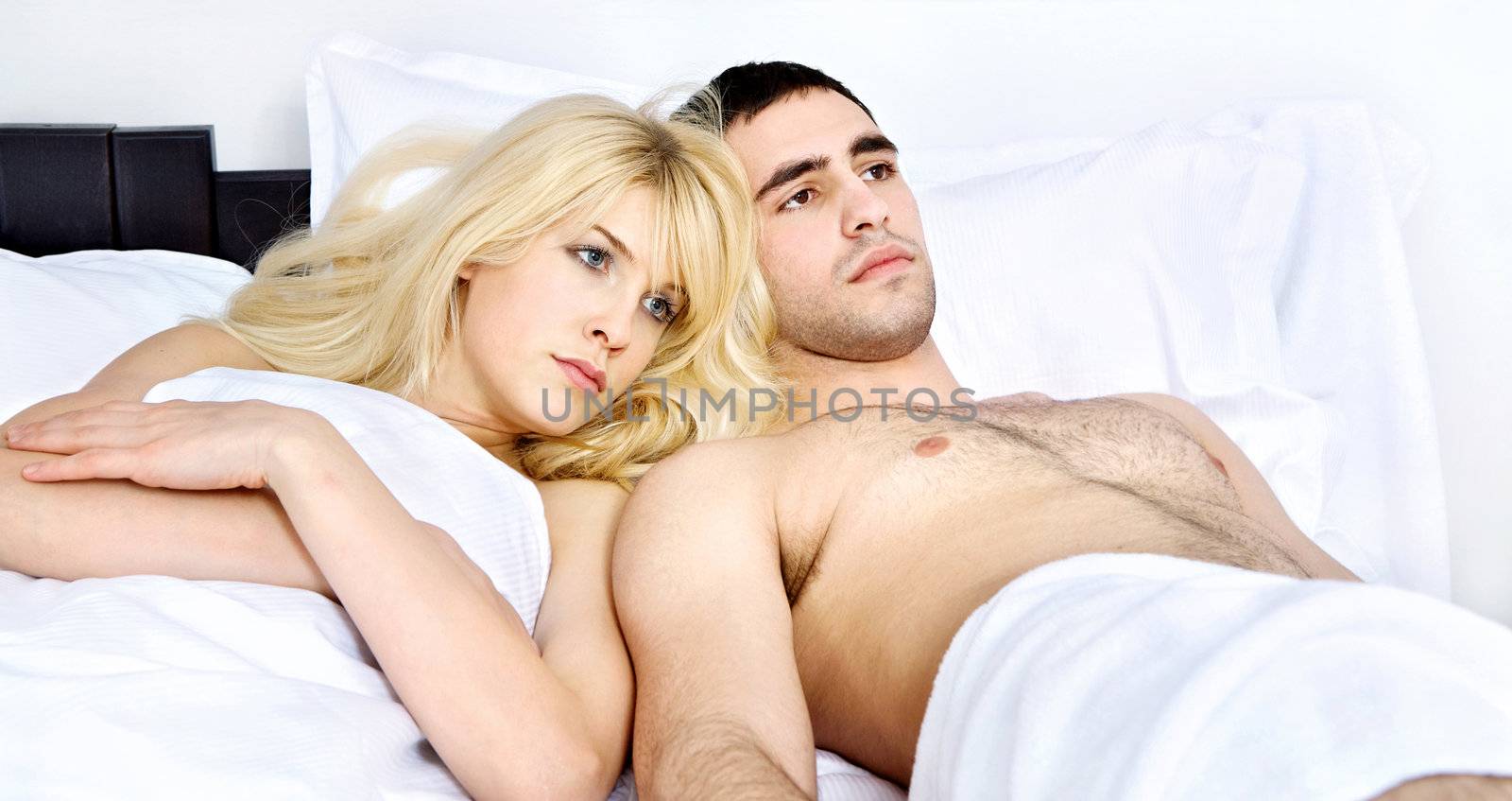 Young heterosexual couple breaking up in bedroom, focus on female