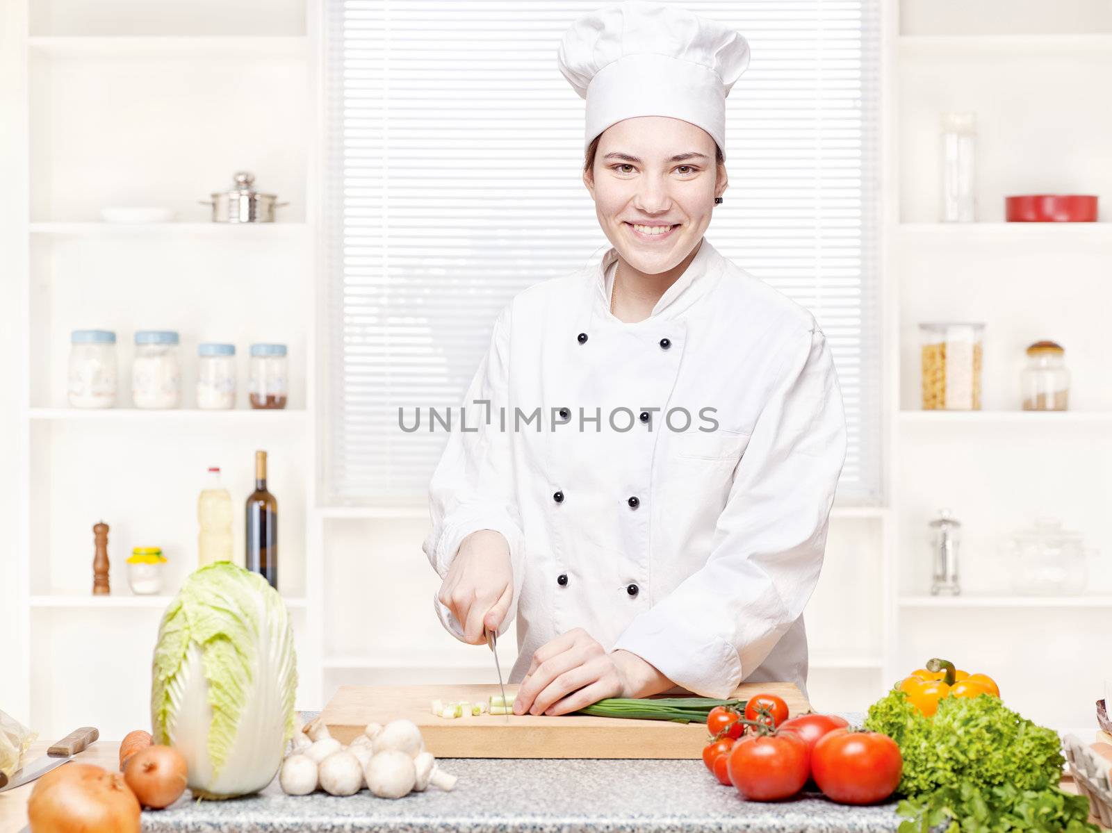 female chef cutting onions on the cutting board in kitchen by imarin