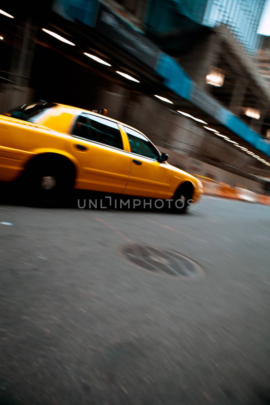 Pnned motion blur of a city street scene with a yellow taxi cab speeding by. 