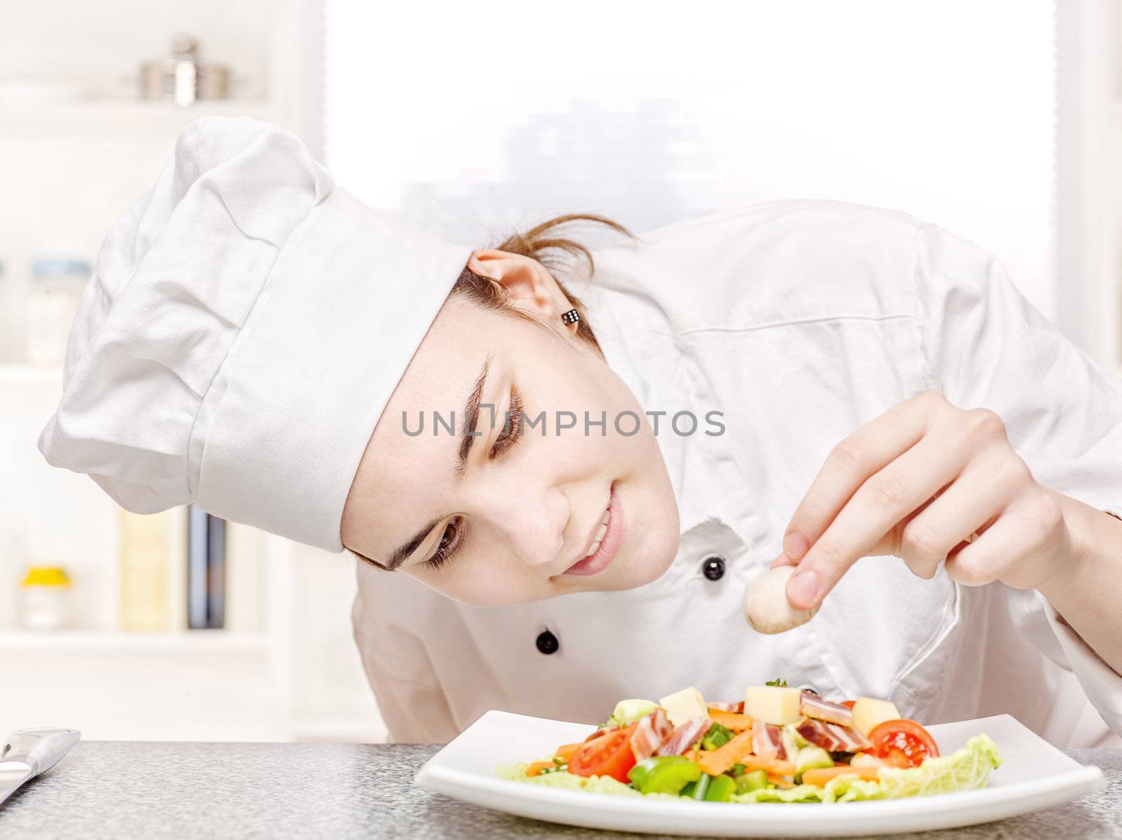 young chef decorating delicious salad by imarin