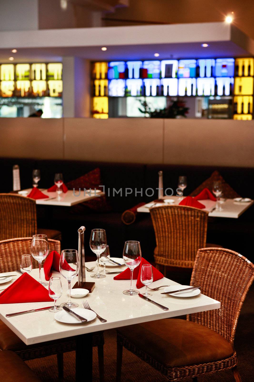 Table settings for dinner with colourful linen and wineglasses in an empty restaurant interior