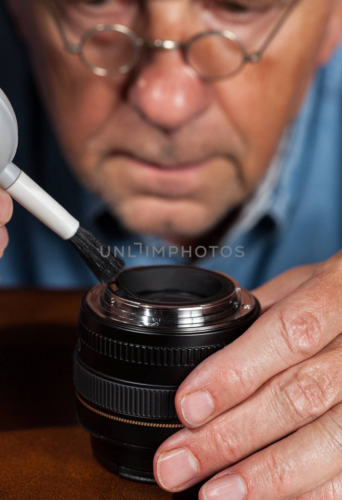 Senior caucasian repairman working a modern camera lens