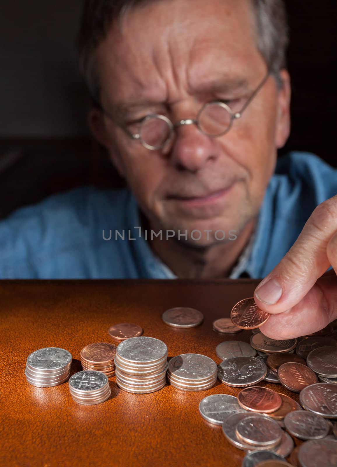 Senior retired caucasian man counting out cash into piles