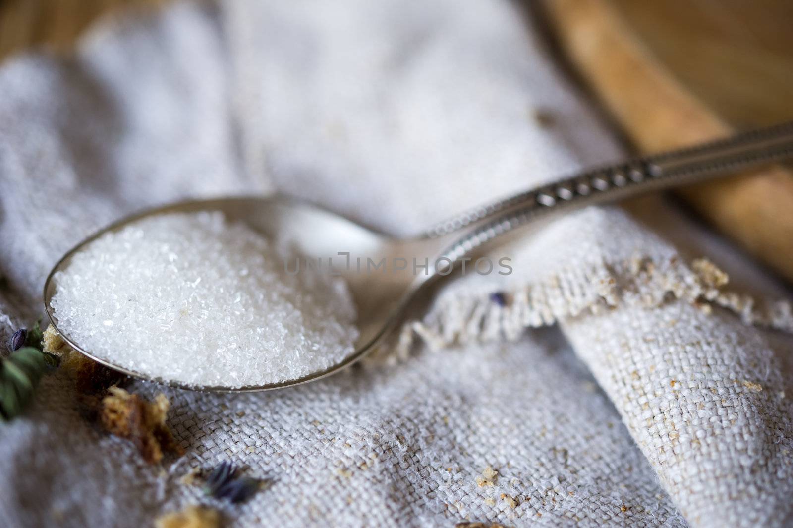 Macro still-life of tea spoon with white sugar on the linen fabric. Shallow DOF