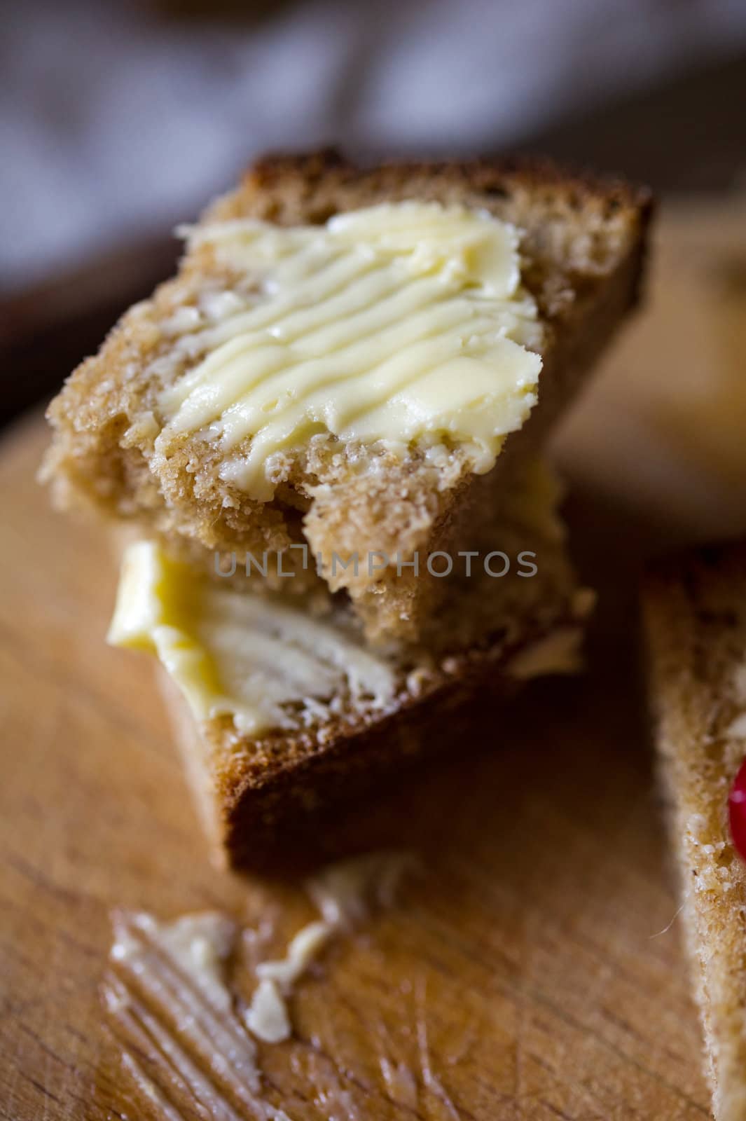 Small sliced piece of wheat bread and butter on the wooden table. Shallow DOF