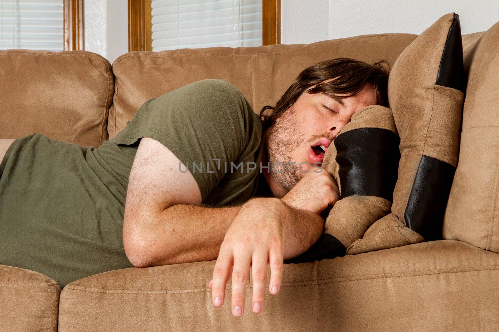 He is asleep mouth open and arm just flung over the side of the couch. 