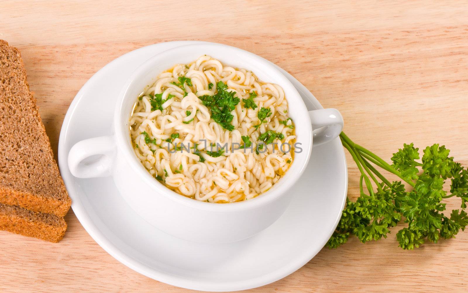 Noodles and parsley soup on plate, bread