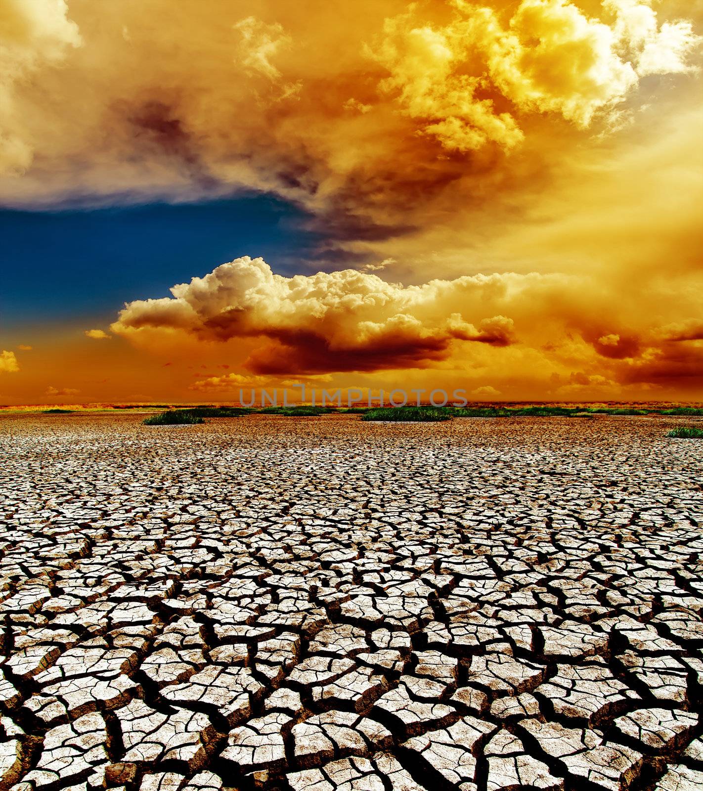 dramatic sunset over dry cracked earth by mycola