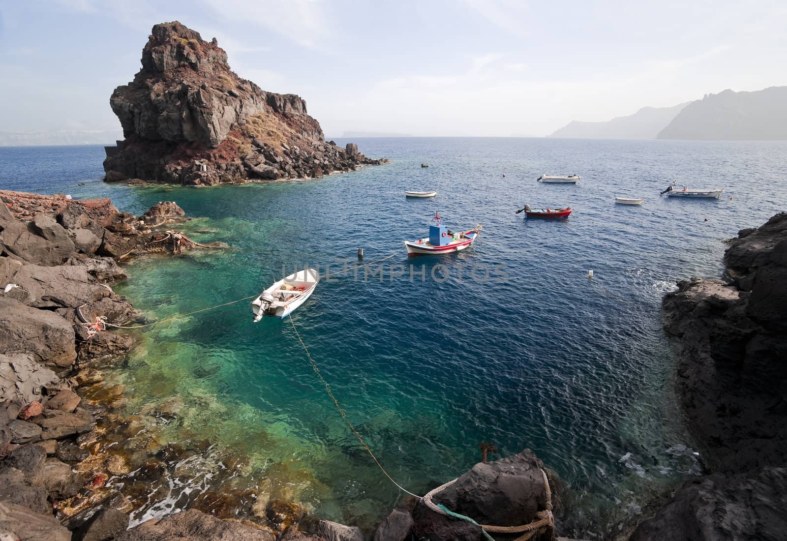 Fish-boats in the beautiful water near the pebble beach