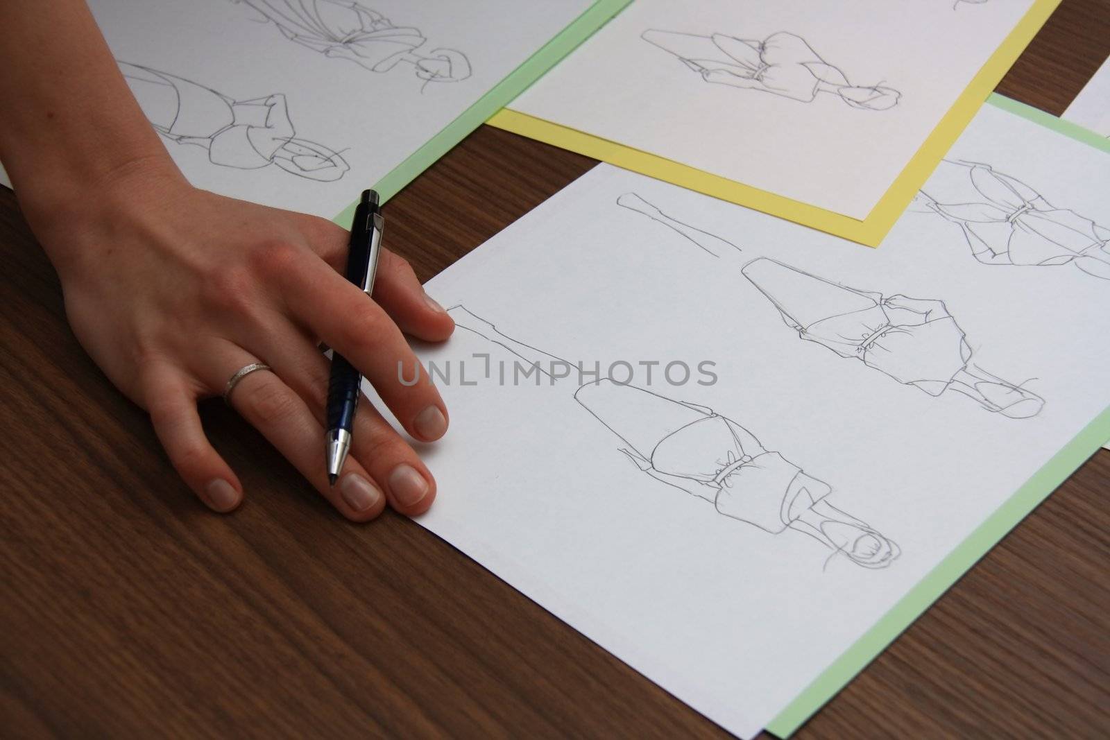 designer assessing fashion drawings on the collection of clothes