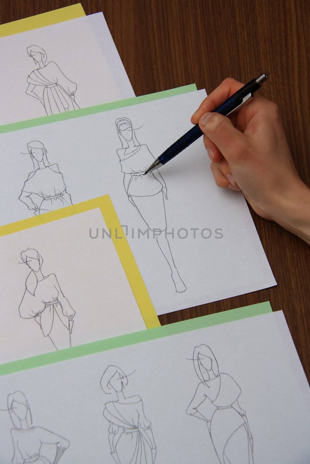 designer assessing fashion drawings on the collection of clothes