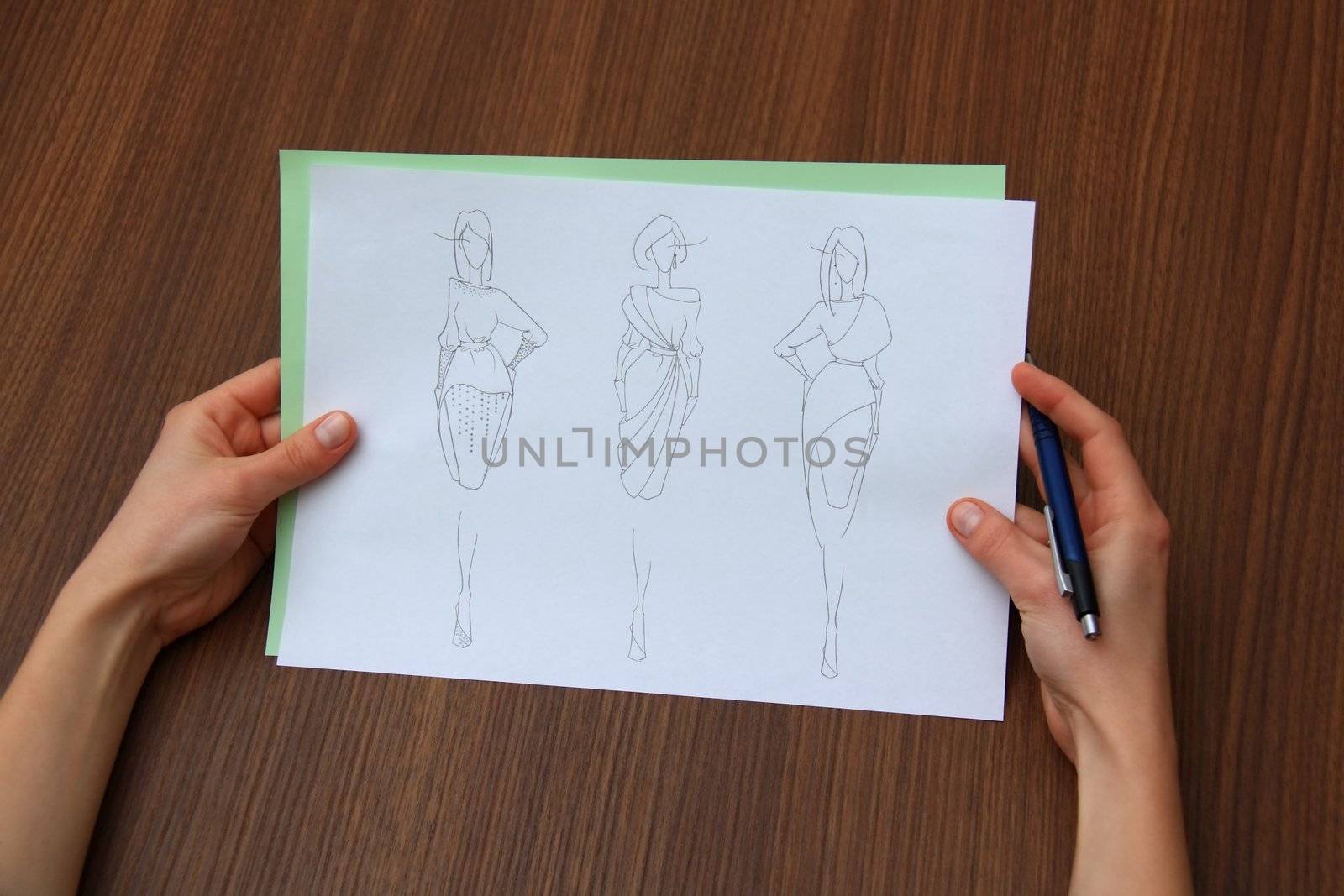 designer assessing fashion drawings on the collection of clothes