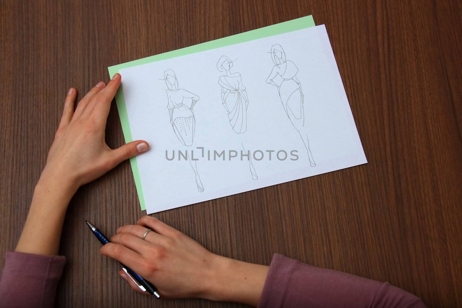 designer assessing fashion drawings on the collection of clothes