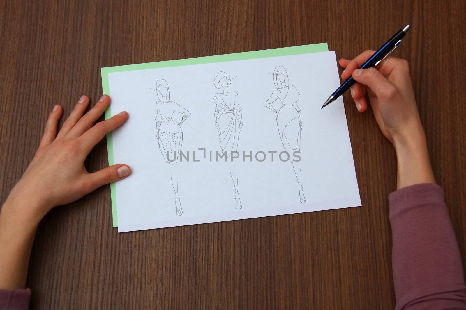 designer assessing fashion drawings on the collection of clothes