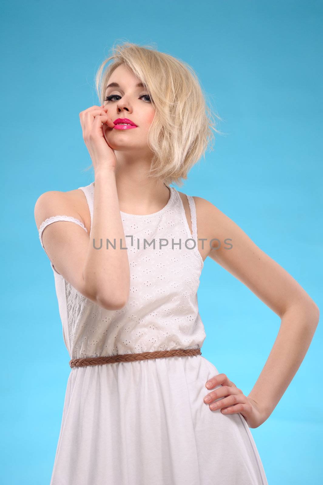 Sensual portrait of a beautiful blonde hair woman with white dress on blue background
