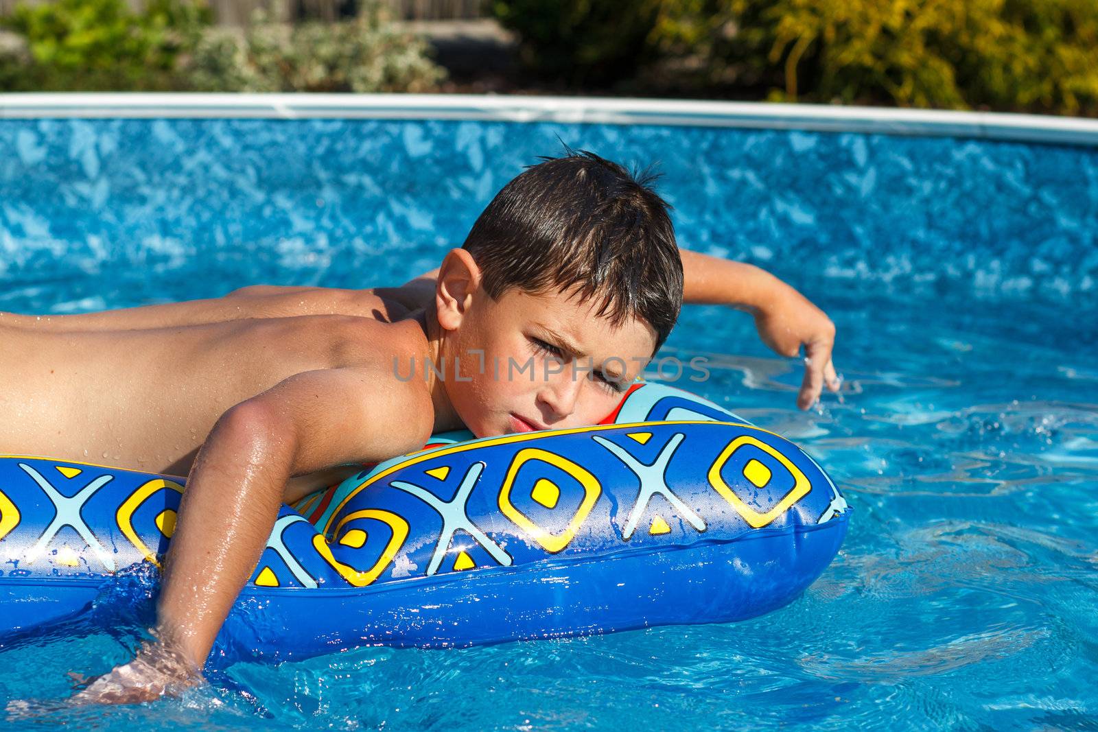 Boy with inflatable water lounger in the swimming pool