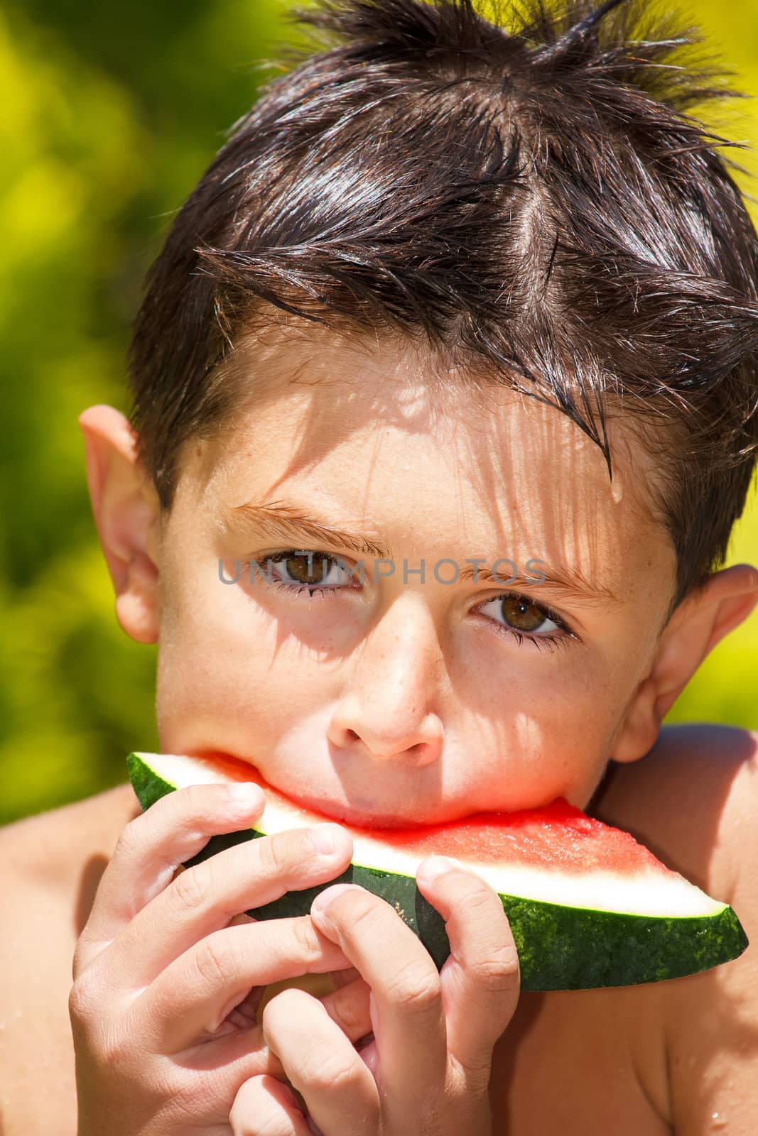 wet boy with watermelon in the garden after swimming