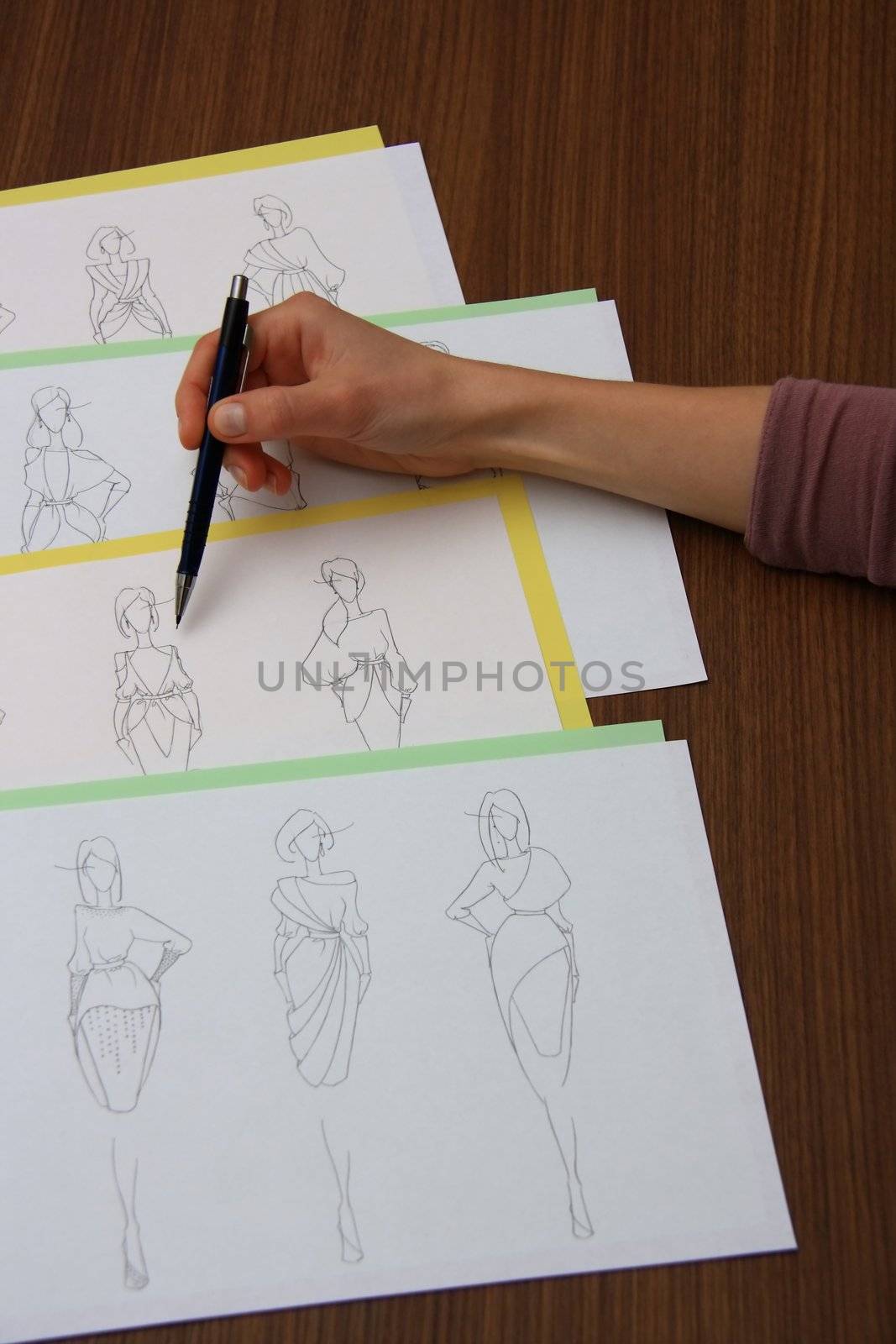 designer assessing fashion drawings on the collection of clothes