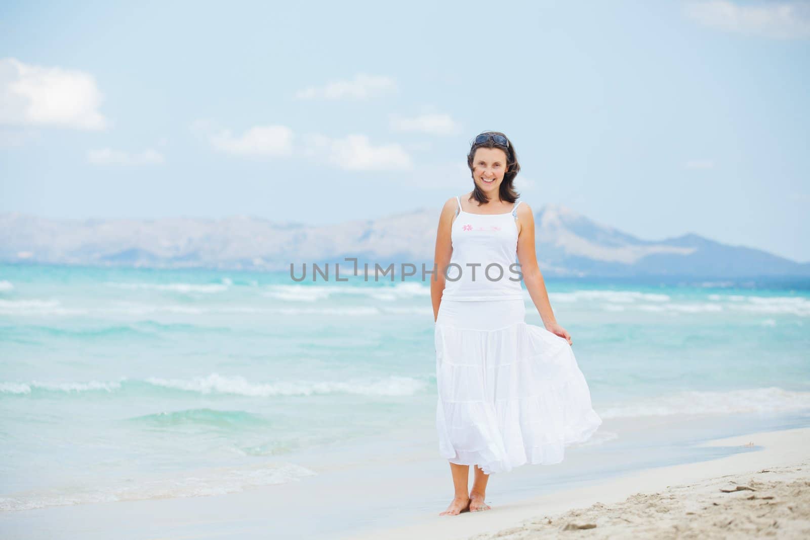 Handsome young woman walking near blue sea.