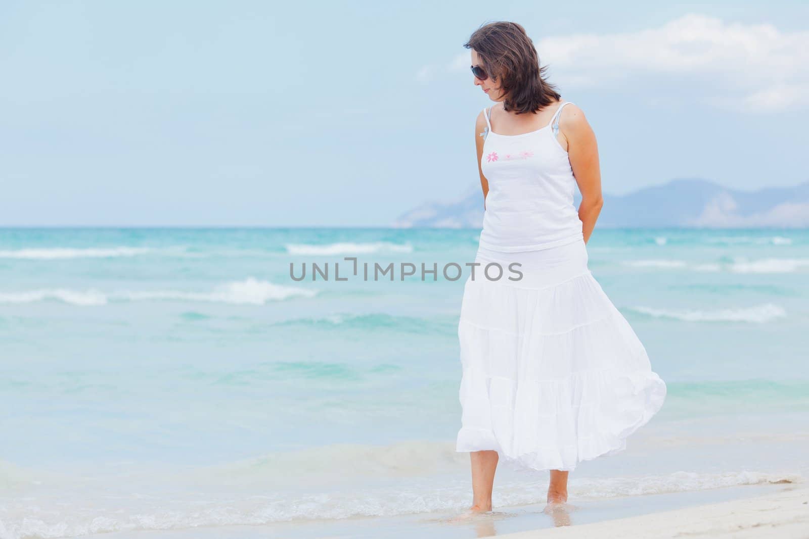 Handsome young woman walking near blue sea.