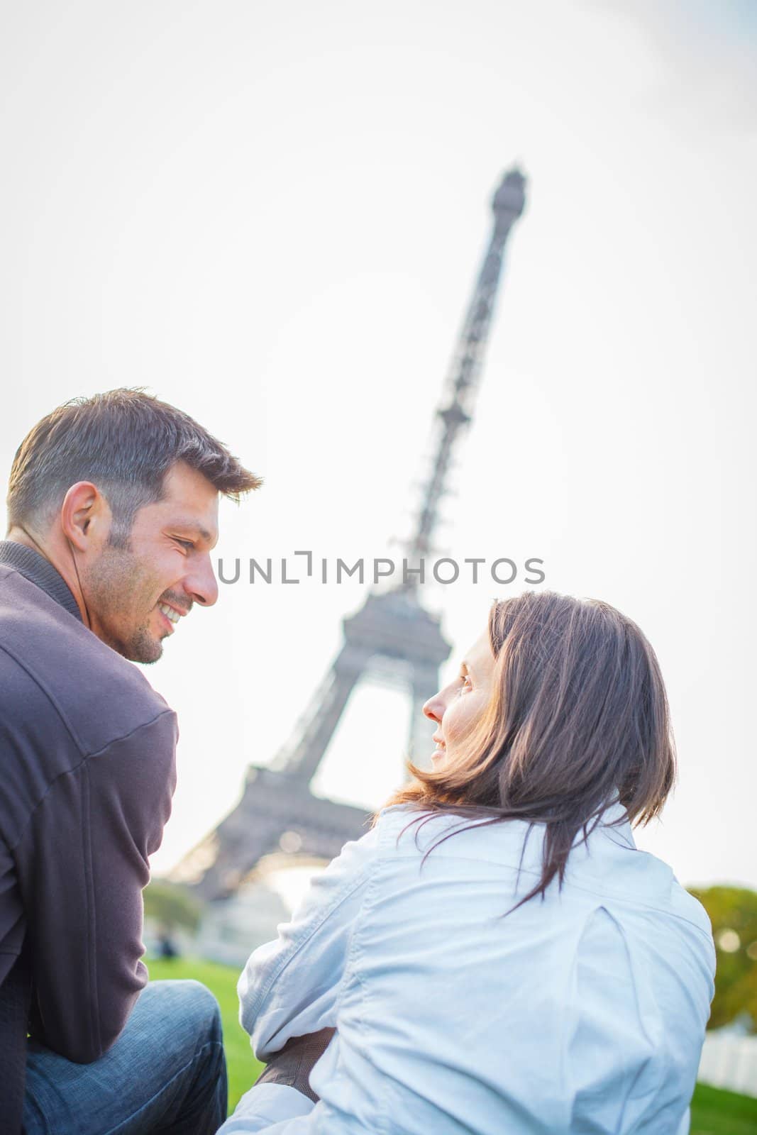 Young romantic couple sitting near the Eiffel Tower in Paris