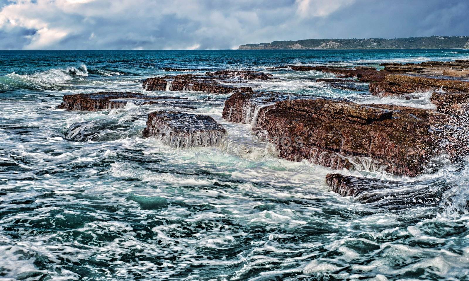 strong waves crashing onto rocks at the coast