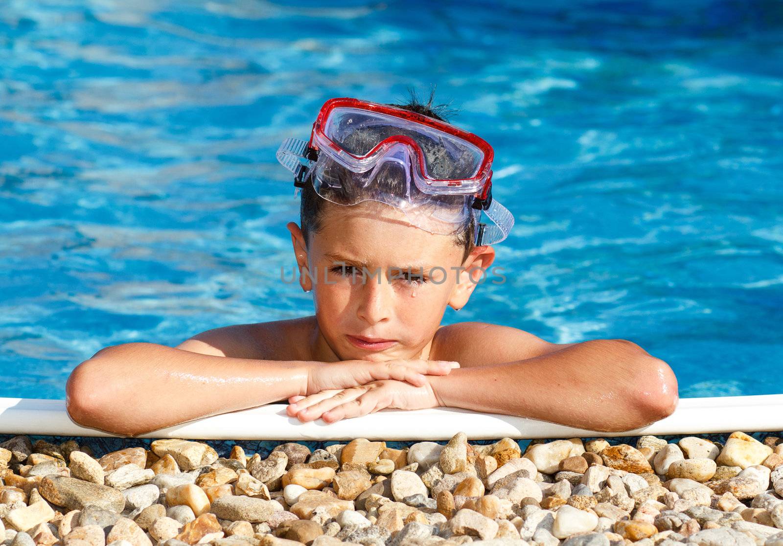 Boy with spectacles in the swimming pool with clear water