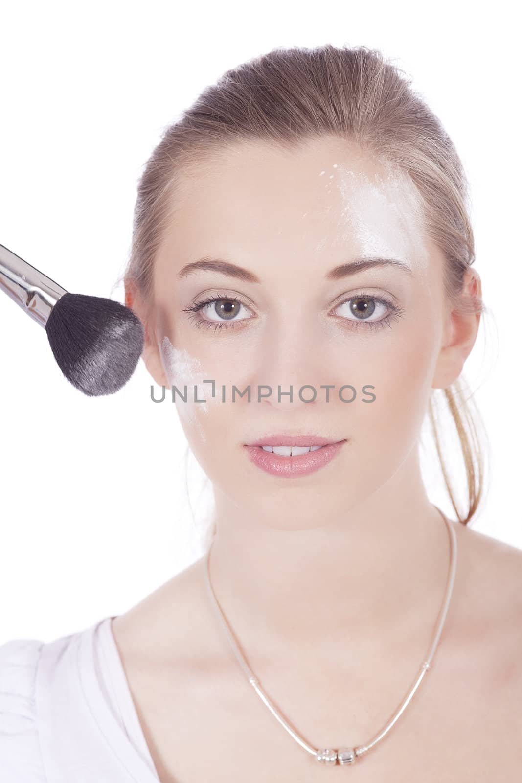 young beautiful woman applying mineral powder on face isolated