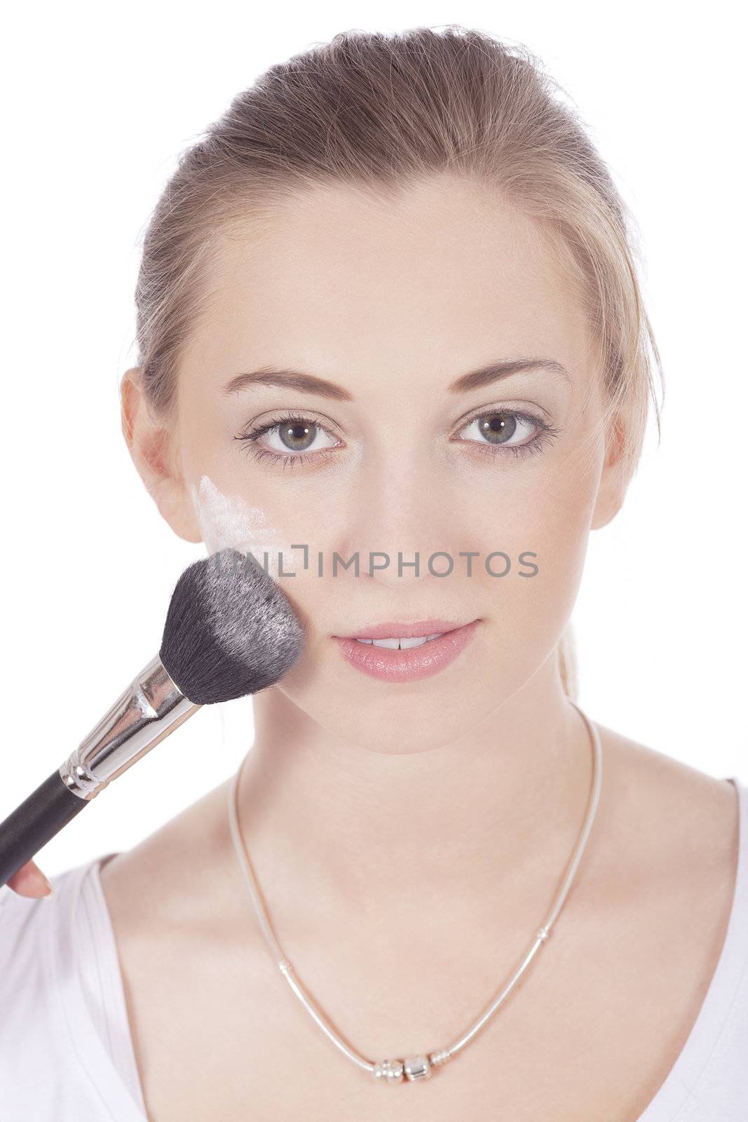 young beautiful woman applying mineral powder on face isolated