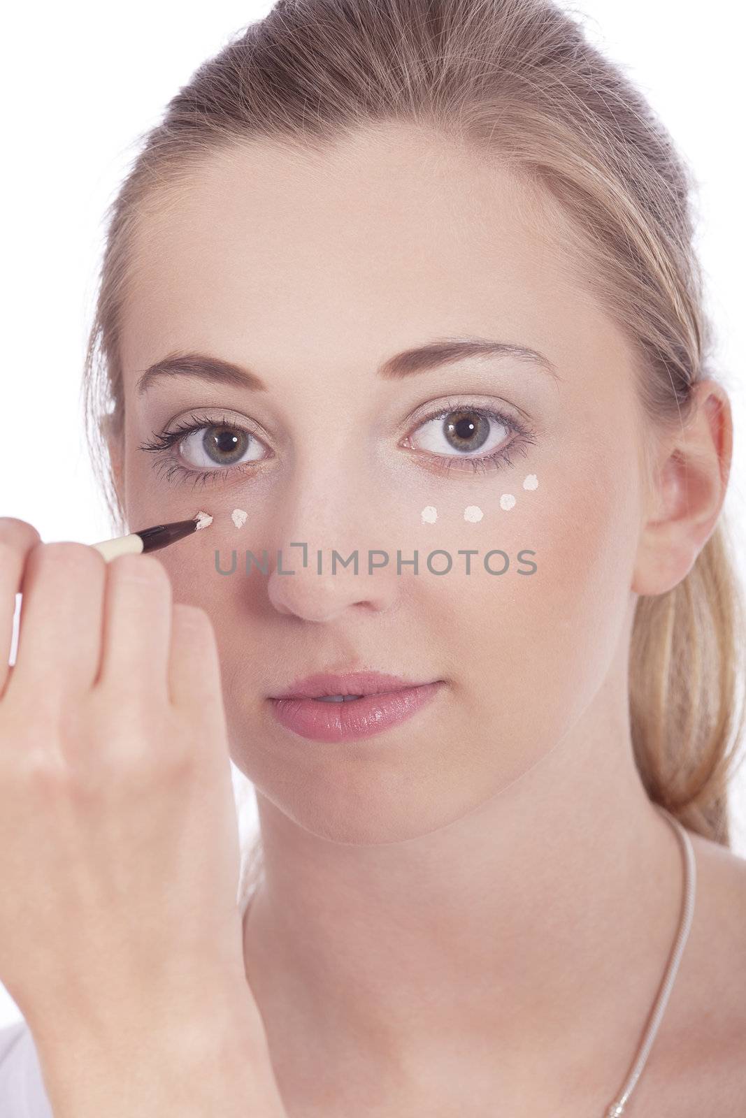 young beautiful woman applying concealer on face isolated