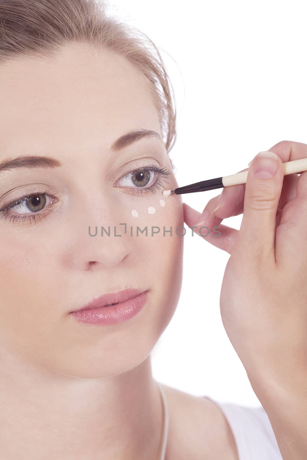 young beautiful woman applying concealer on face isolated