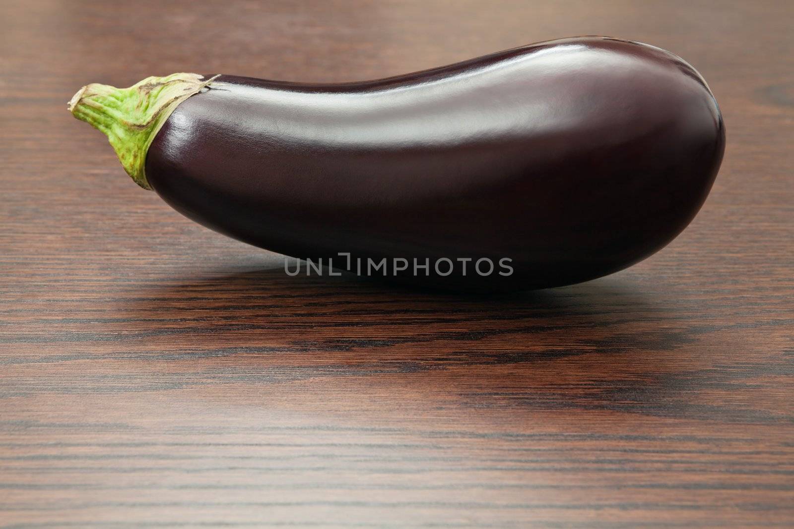 Photo of an eggplant resting on a wood table.