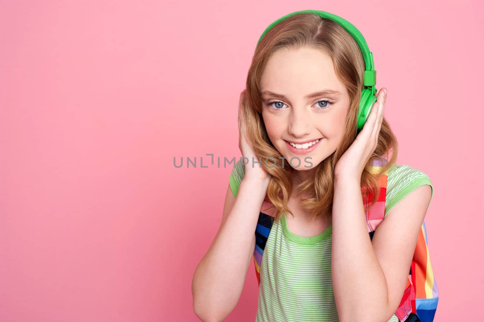 Pretty teenager enjoying music on headphones with bag on her shoulders