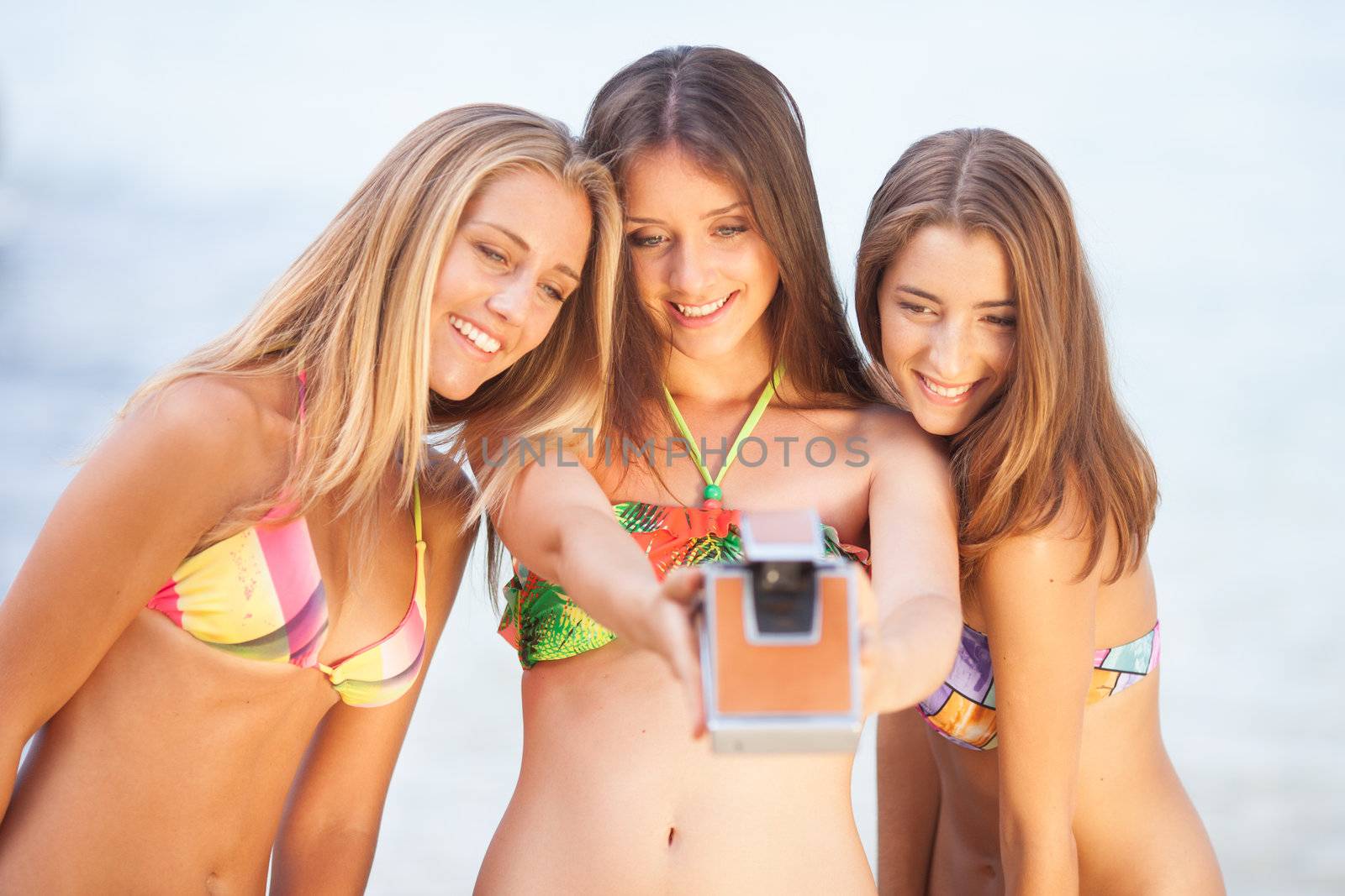 three teenager beautiful girls taking selfie with old camera on the beach by Lcrespi