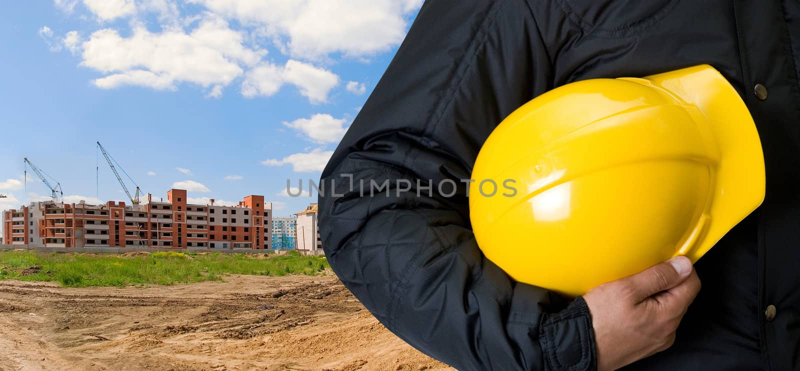 Closeup  of Yellow helmet at builder hands on building background