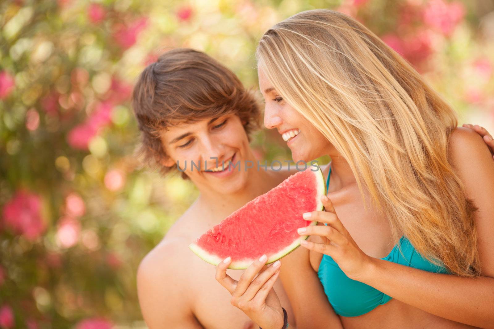 Portrait of a young beautiful couple eating watermelon by Lcrespi