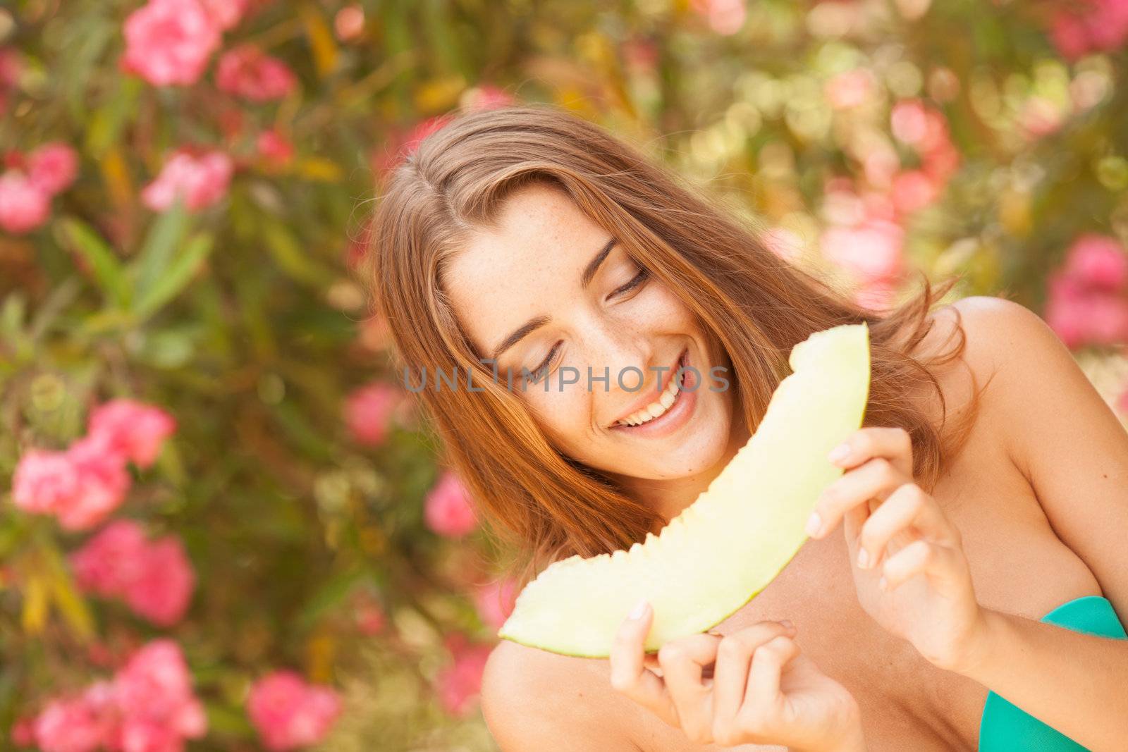 Portrait of a beautiful young woman eating melon