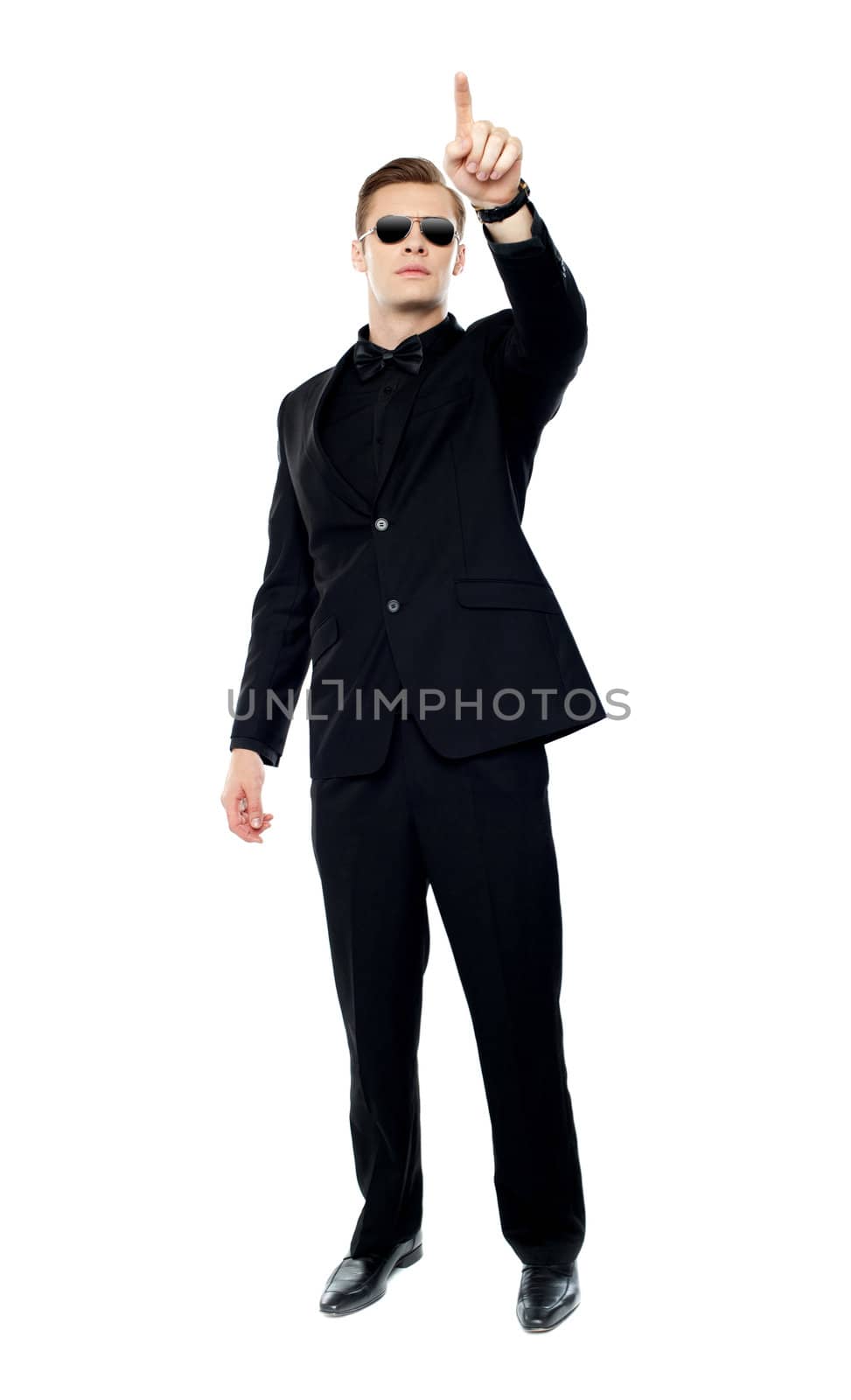 Young handsome man pointing upwards towards copy space area