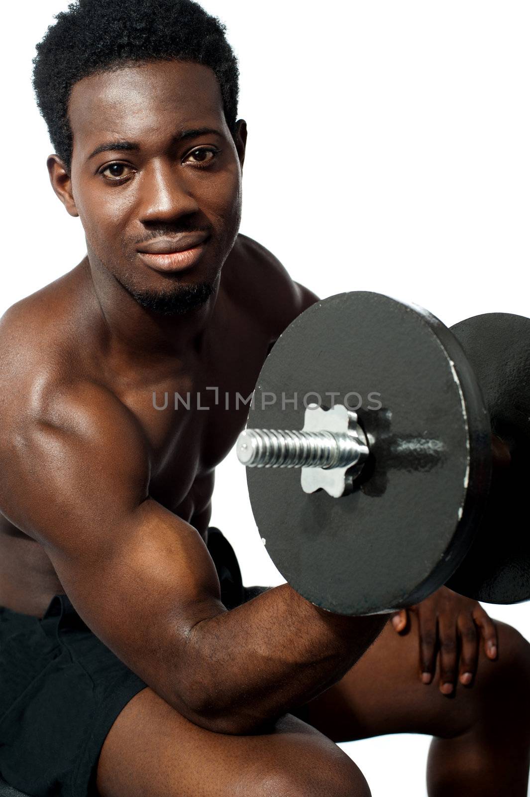 Powerful young man lifting weights. Looking at camera while exercising