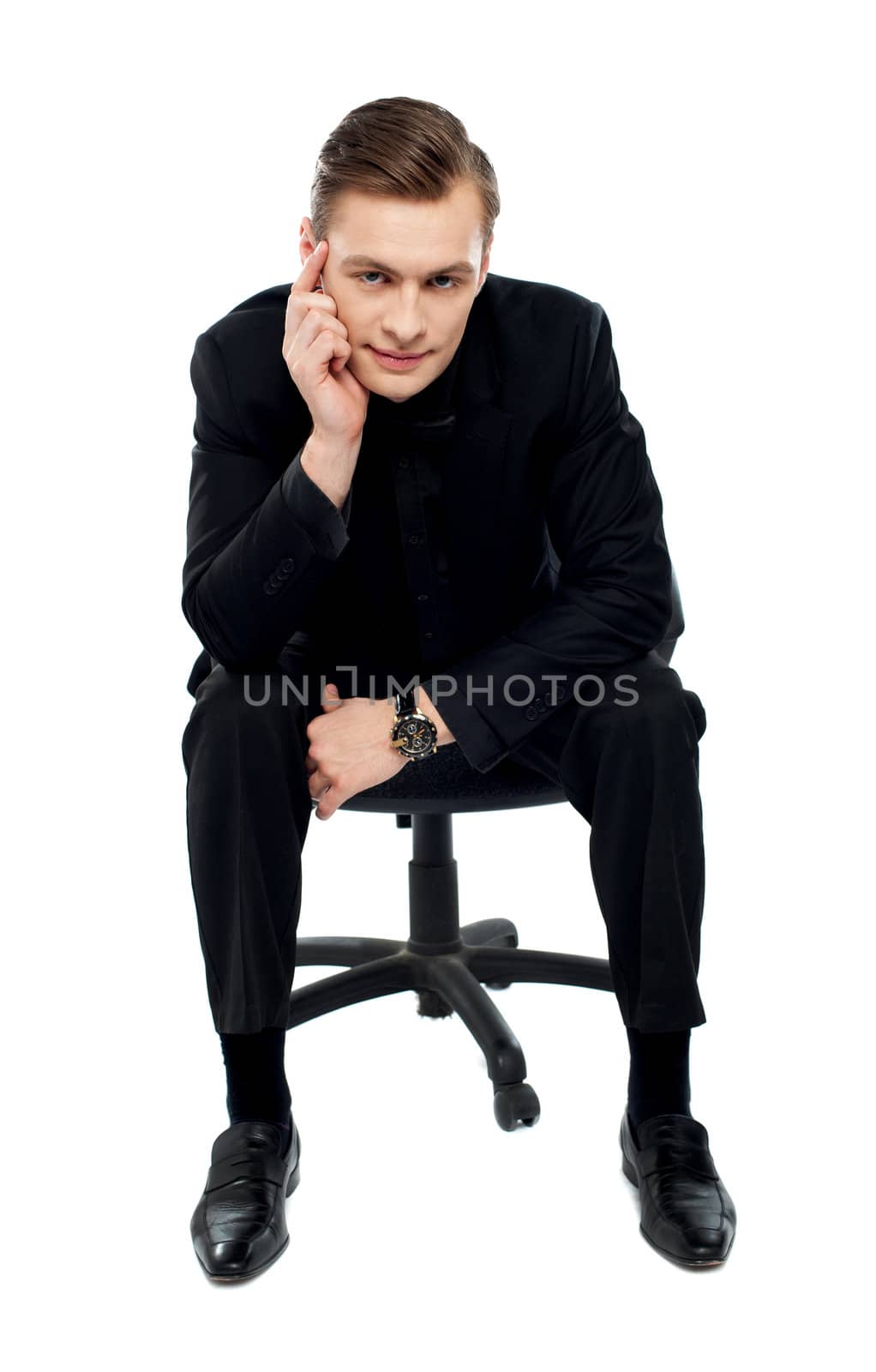Handsome young caucasian male sitting on chair. Looking at camera