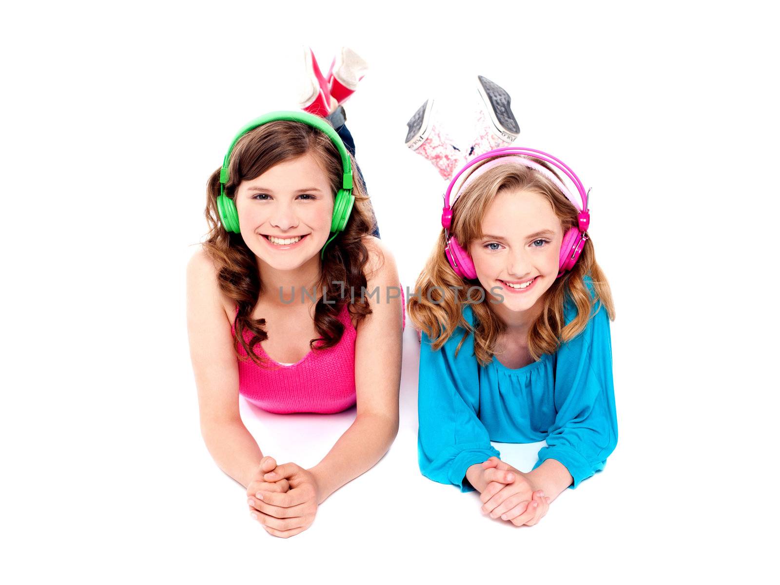 Two beautiful girls lying on floor wearing headphones and enjoying music