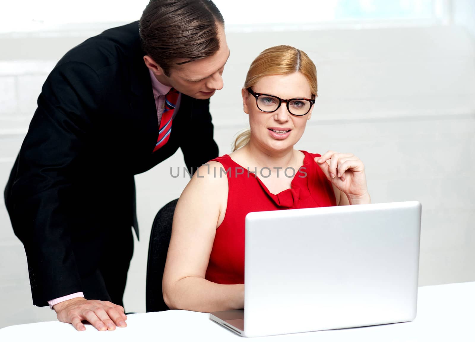 Young business team working in office. Woman operating laptop while man standing behind her