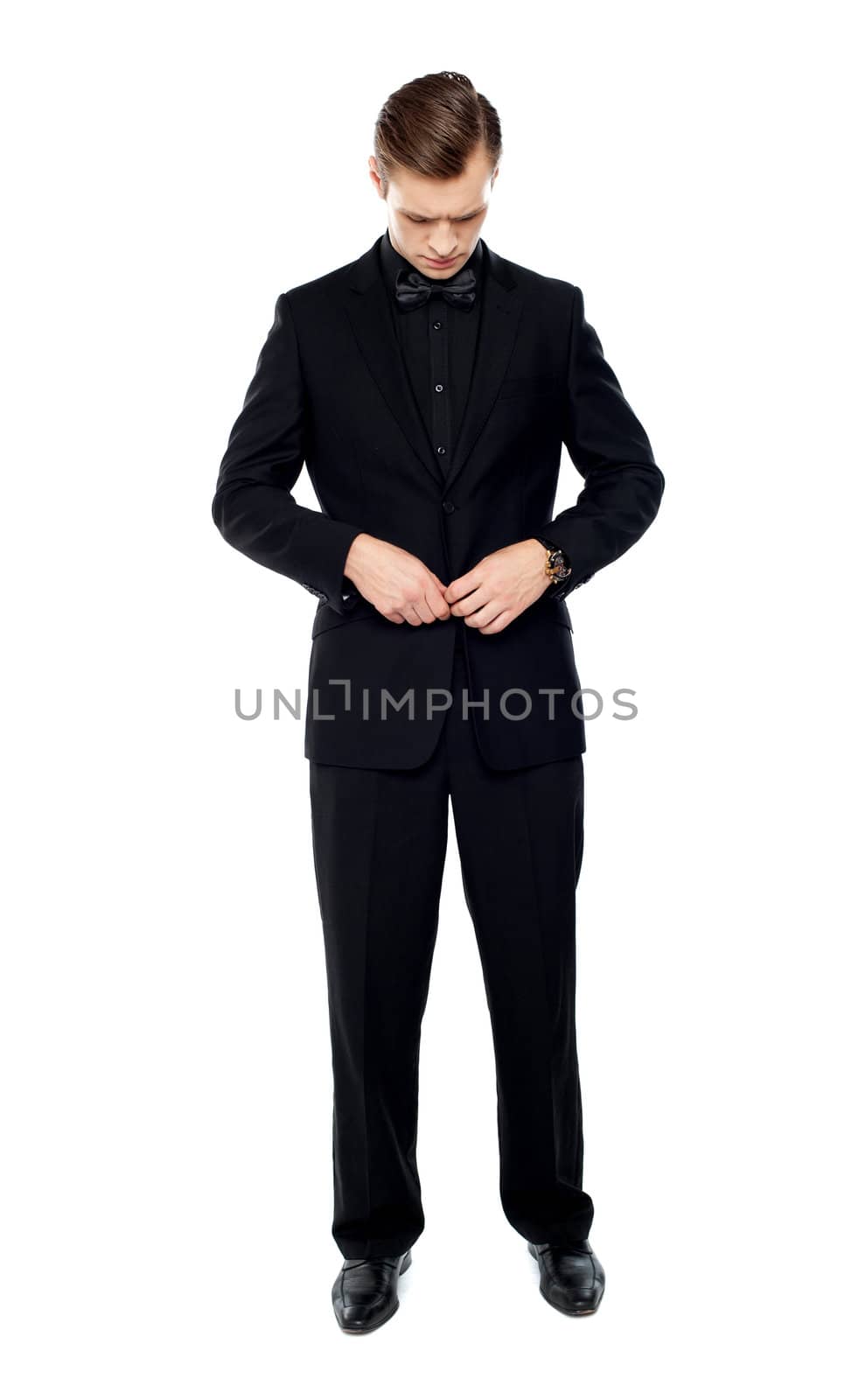 Full length portrait of handsome young gentleman tucking his coat button
