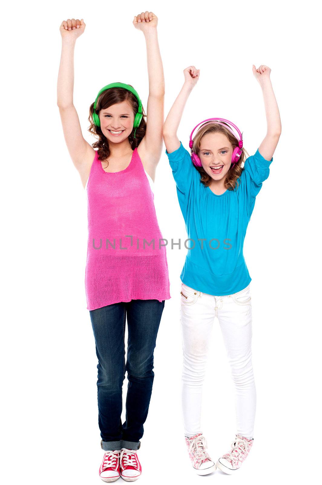 Excited young girls enjoying music together isolated over white. Full length portraits